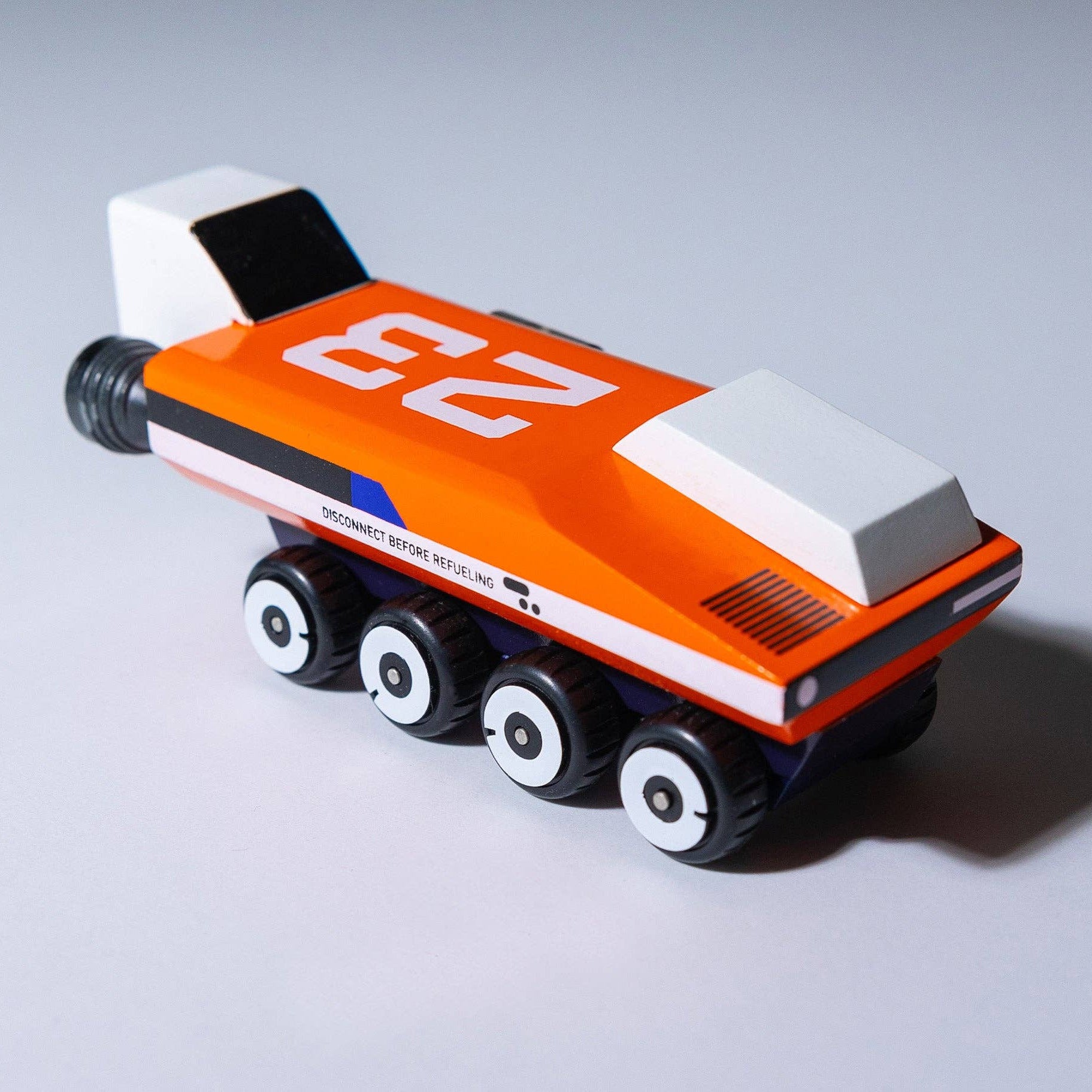 Small orange and white robot-like vehicle on a gray background