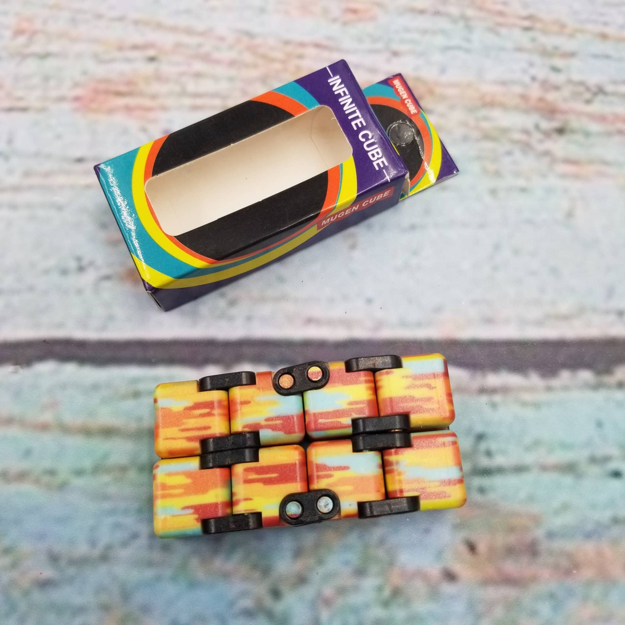 Colorful Infinite Cube toy with packaging on a textured surface