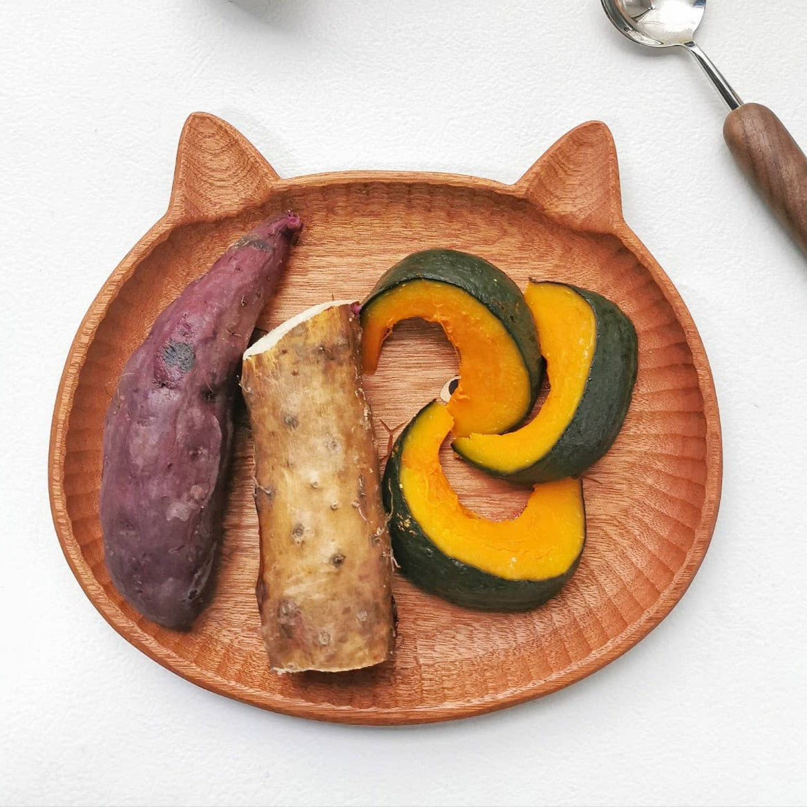 Wooden plate with cat ears holding a variety of food items on a white background