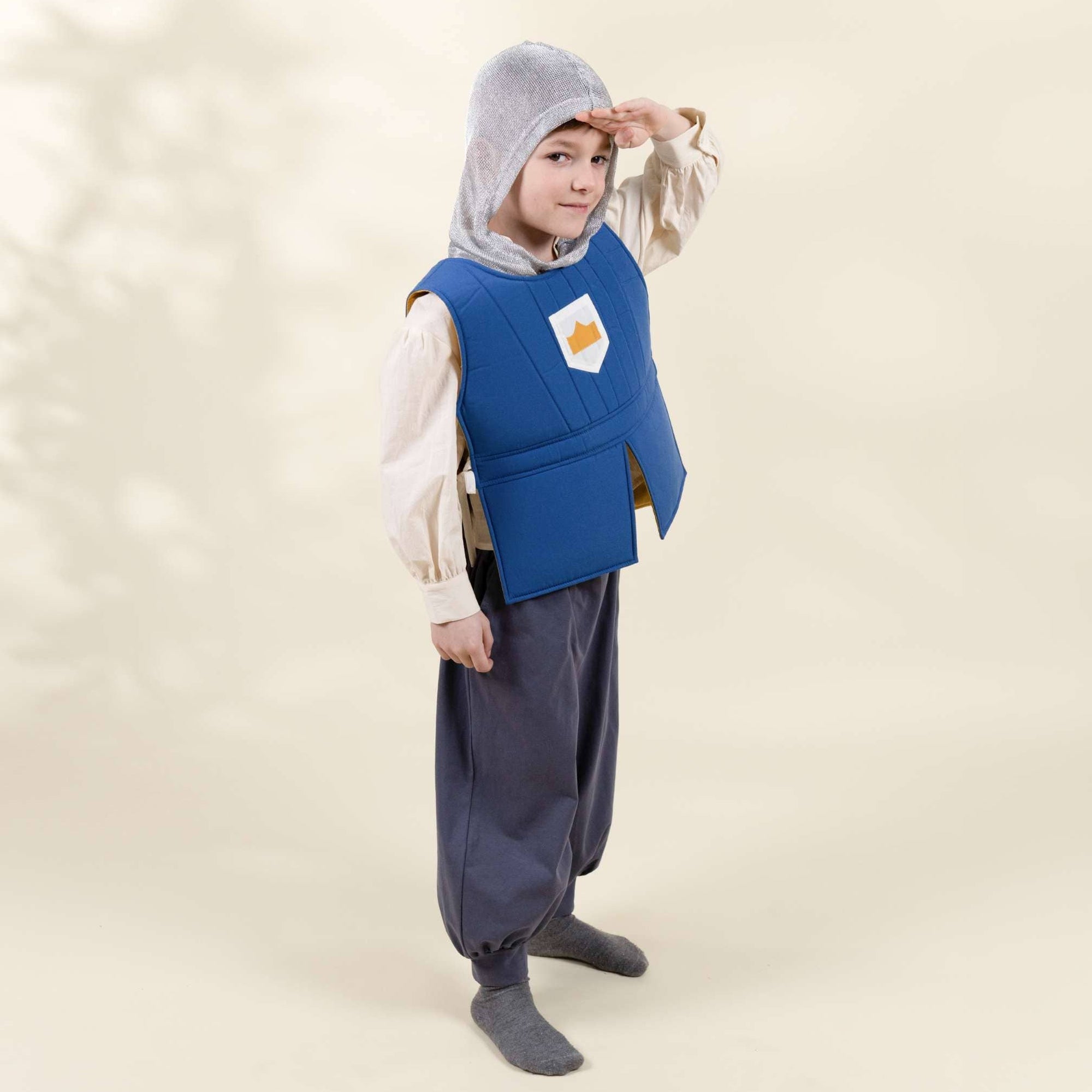 Child wearing a blue vest with a hood on a beige background