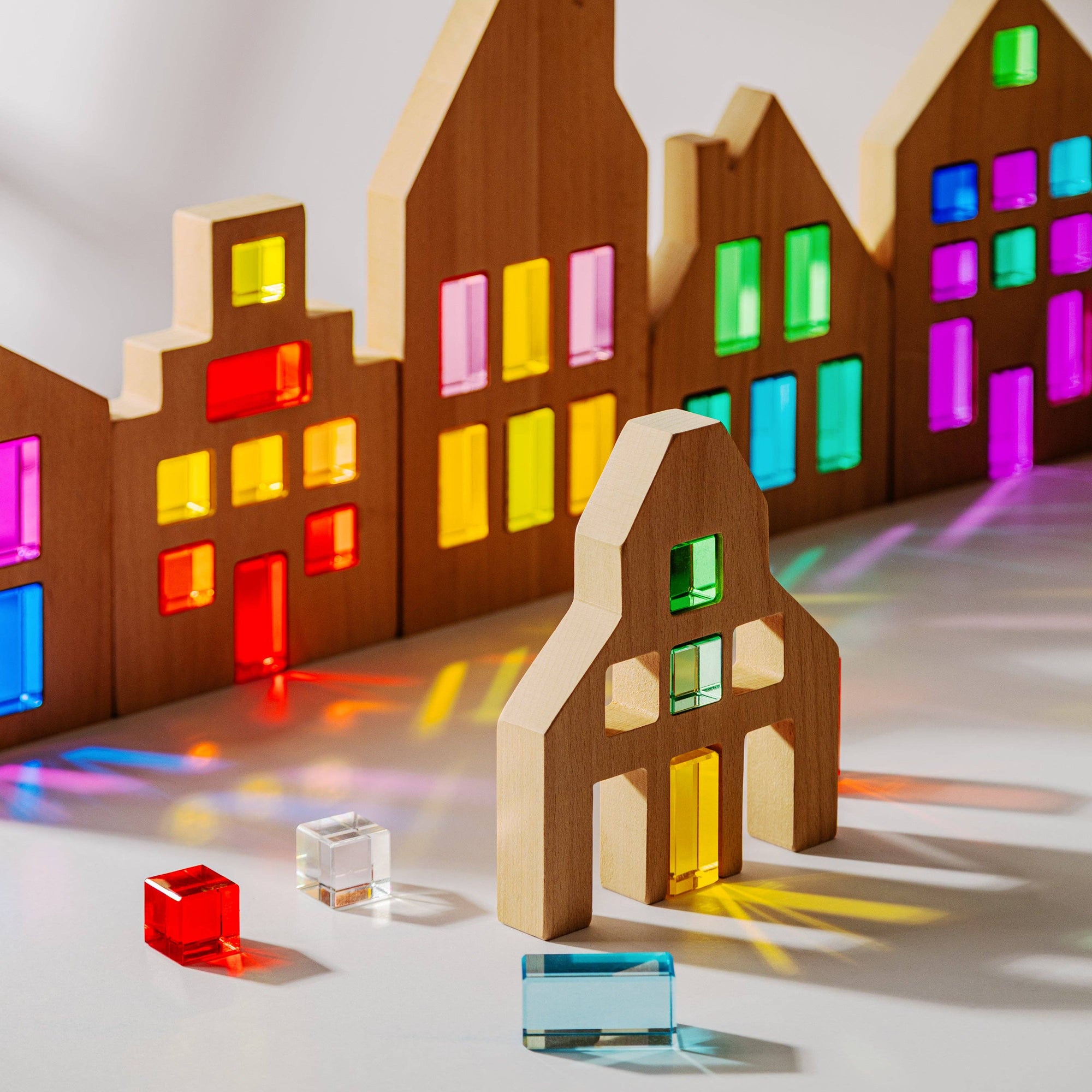 Wooden toy houses with colorful transparent blocks on a reflective surface
