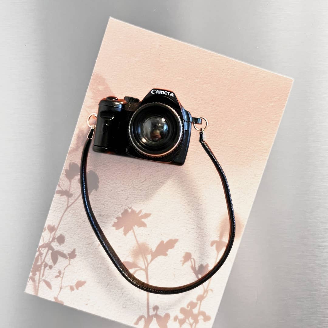 Black camera with a strap on a floral-patterned card