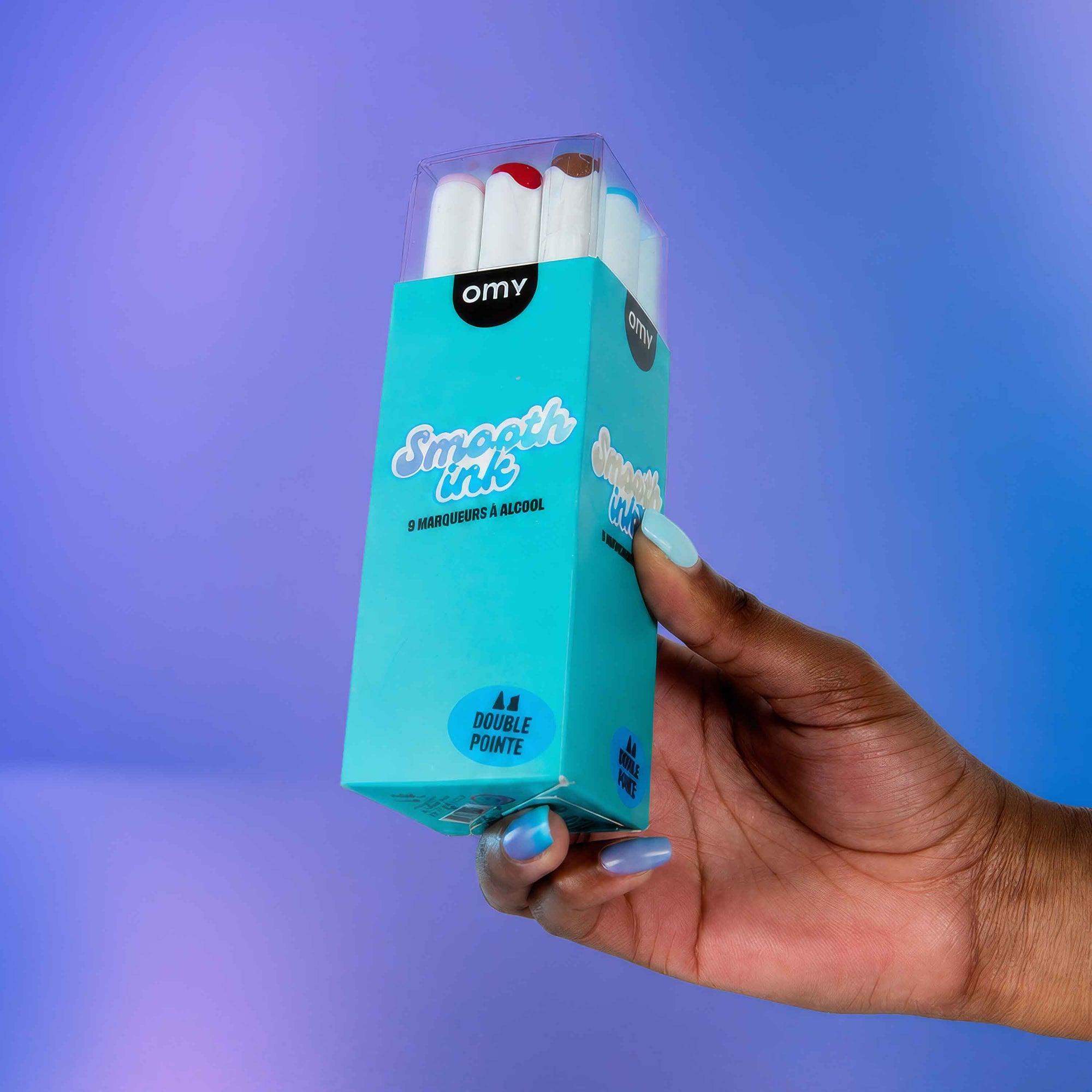 Hand holding a box of OMY Double Pointe dance shoes against a purple background
