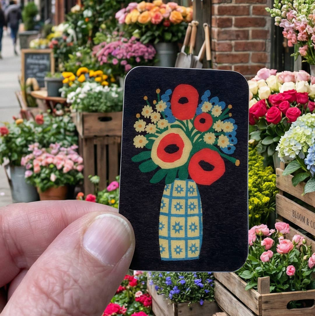 Floral illustration on a small card held over a flower market with various flowers in the background.