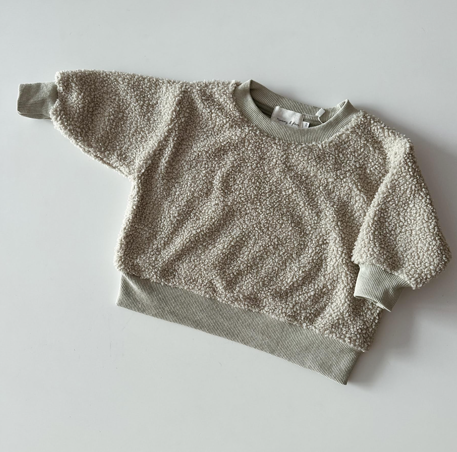 Two-tone sweater with textured top and solid bottom on a light gray background