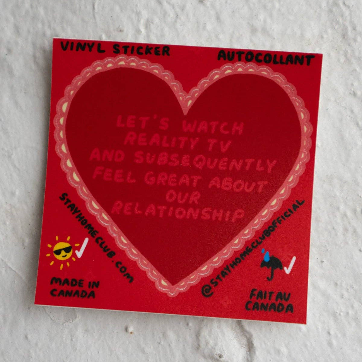 Red vinyl sticker with text on a textured white wall