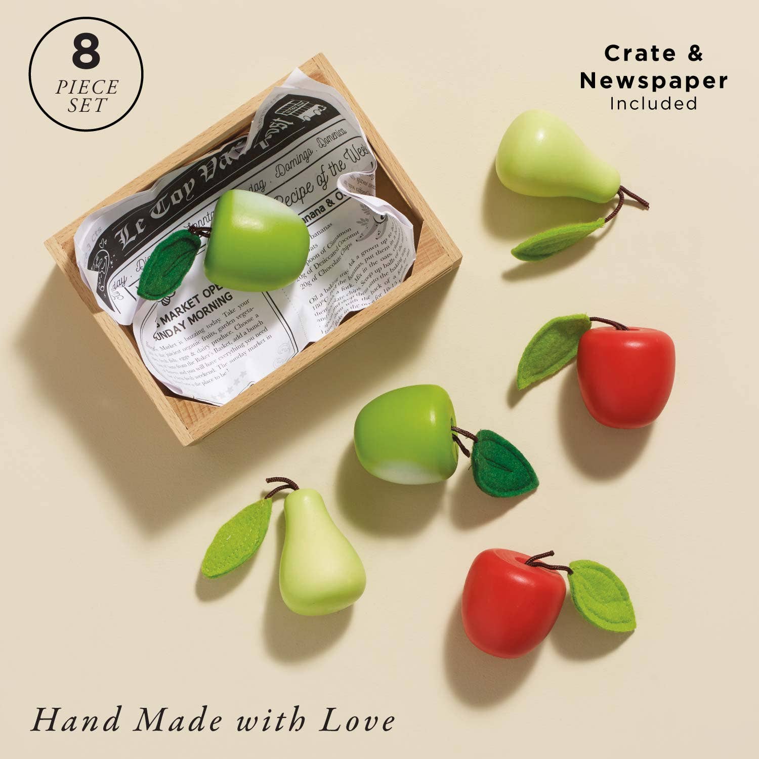 Set of toy fruits including apples and pears in a wooden crate with newspaper, on a beige background.