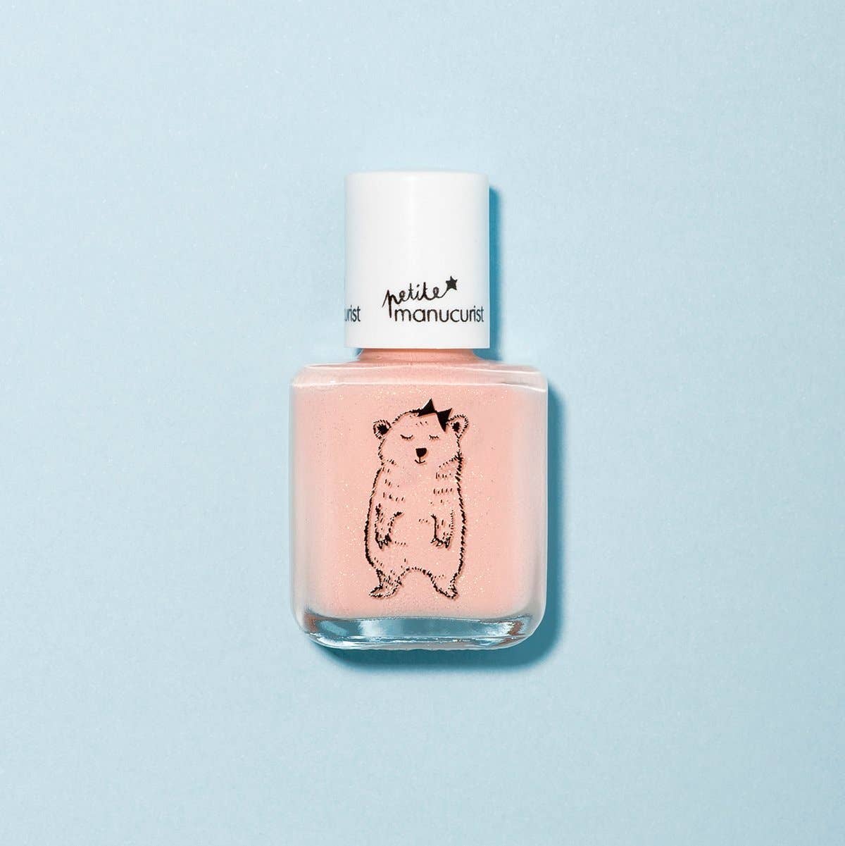 Pink nail polish bottle with a bear design on a light blue background