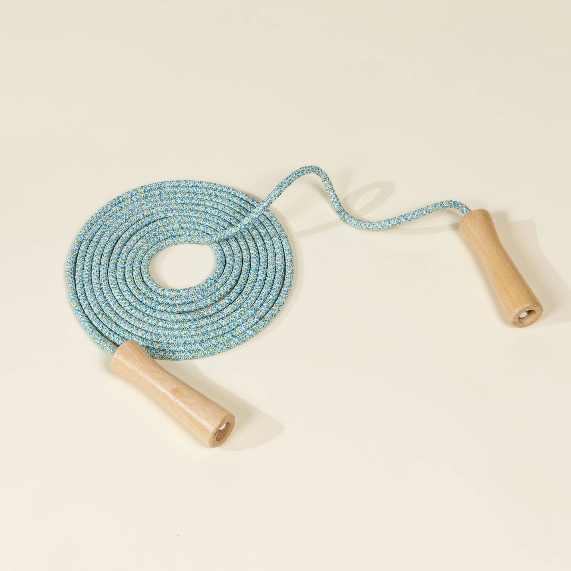 Blue jump rope with wooden handles on a beige background