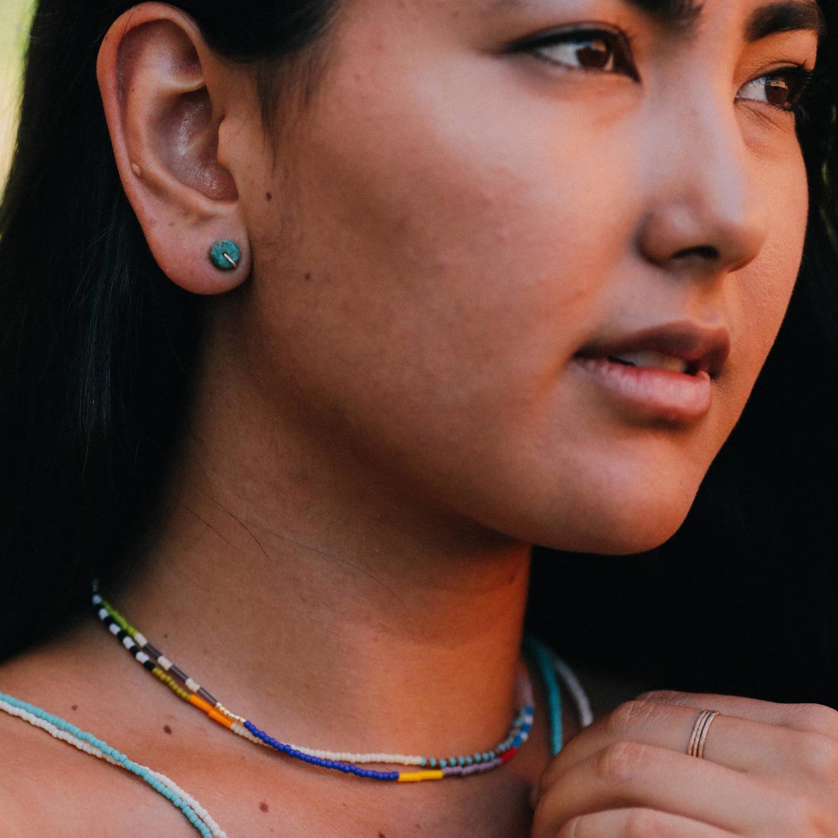 Close-up of a person wearing earrings and a necklace with a blurred background