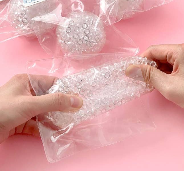 Clear plastic bags filled with small round objects on a pink background