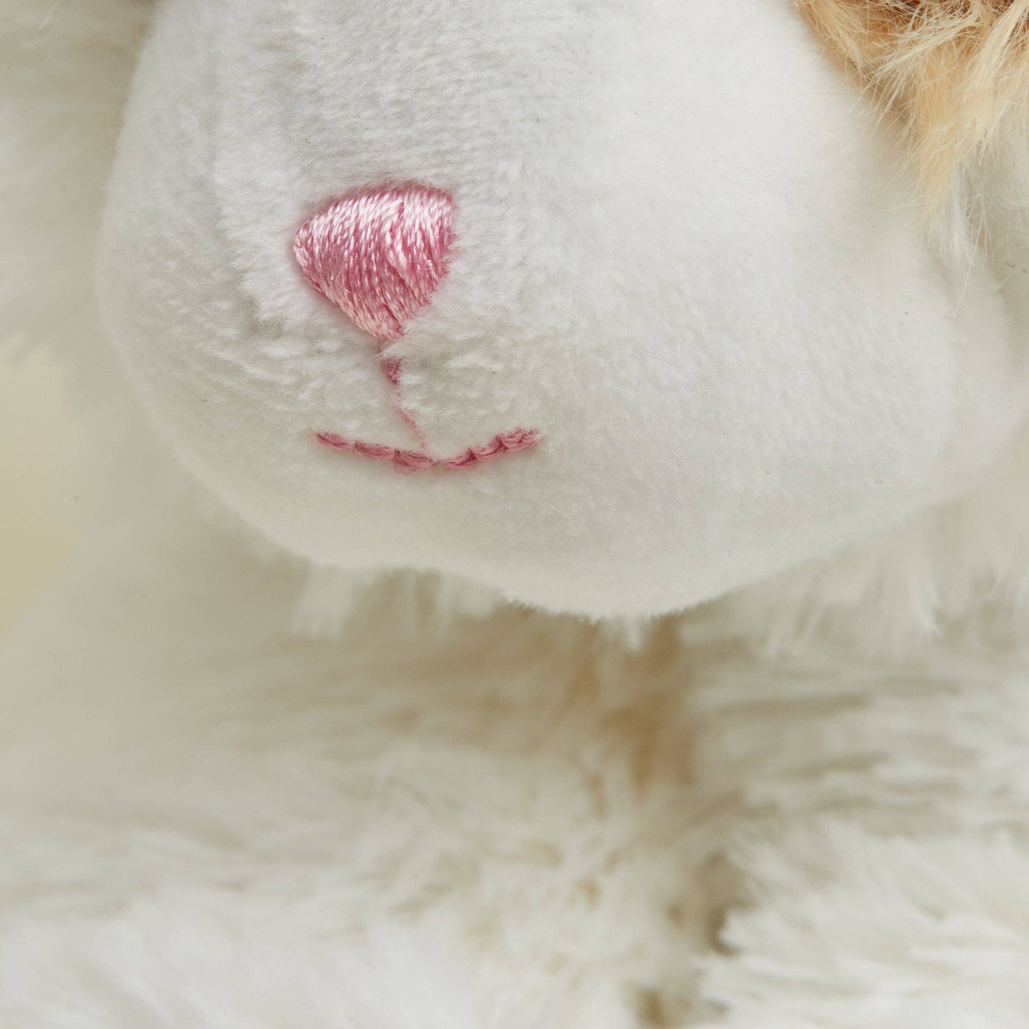 Close-up of a white plush toy with a pink balloon on a soft beige background