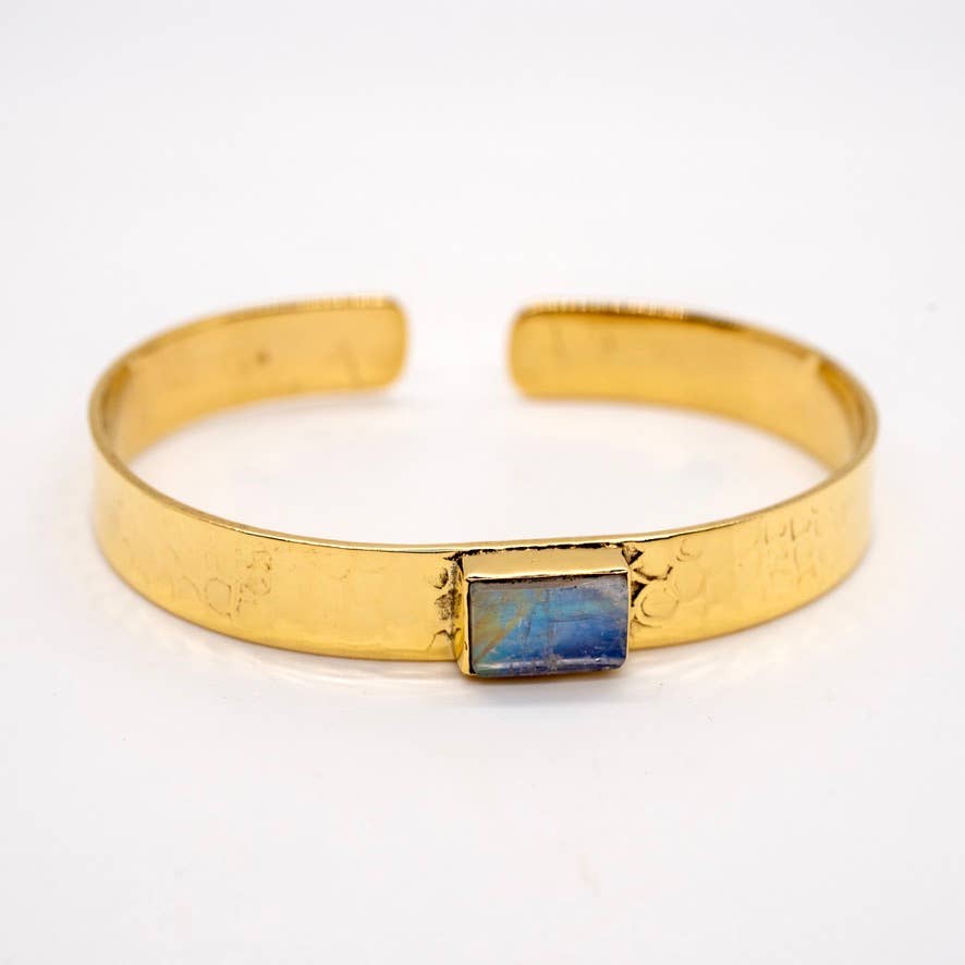 Gold bracelet with a blue stone on a white background