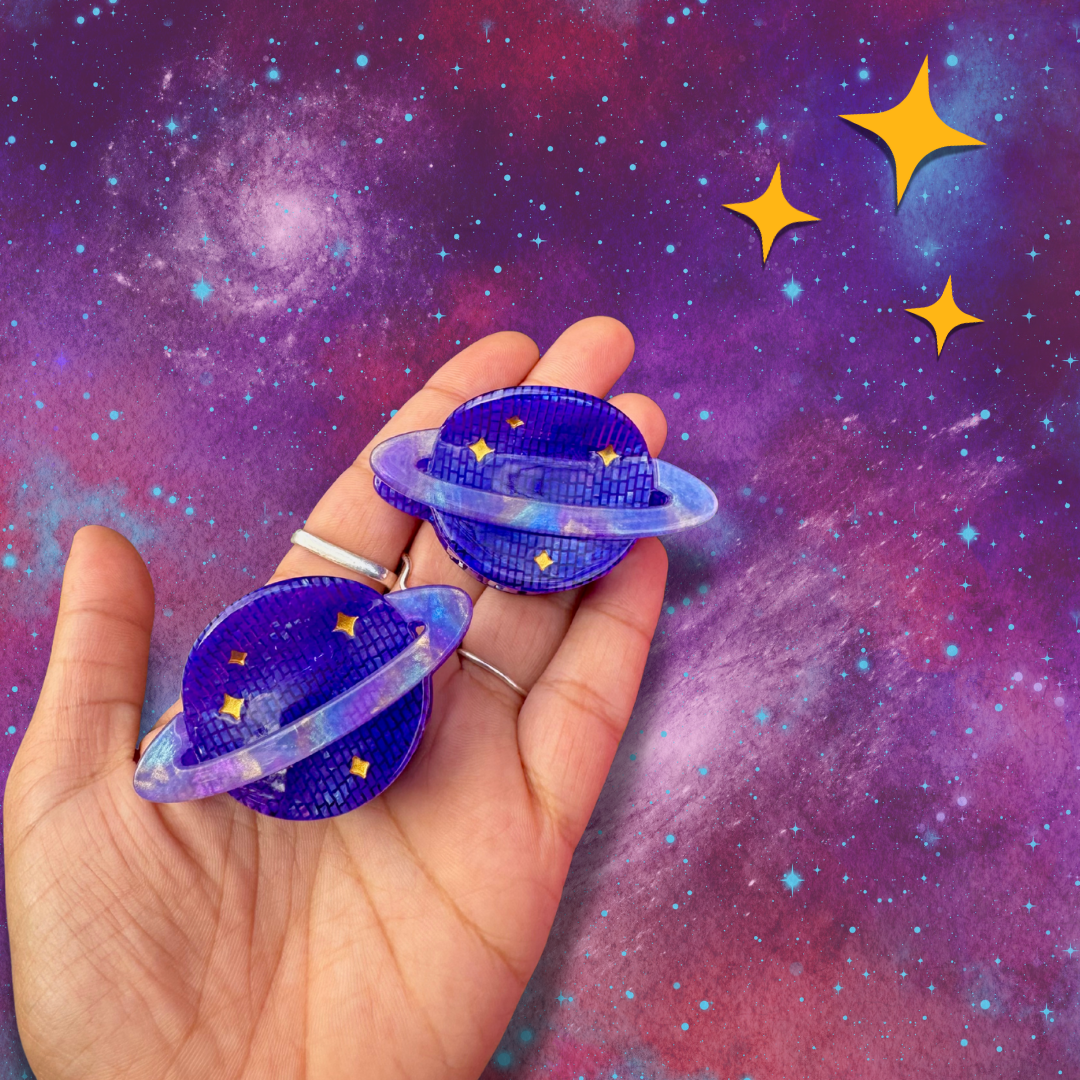 Hand holding two purple planet-shaped objects against a starry space background