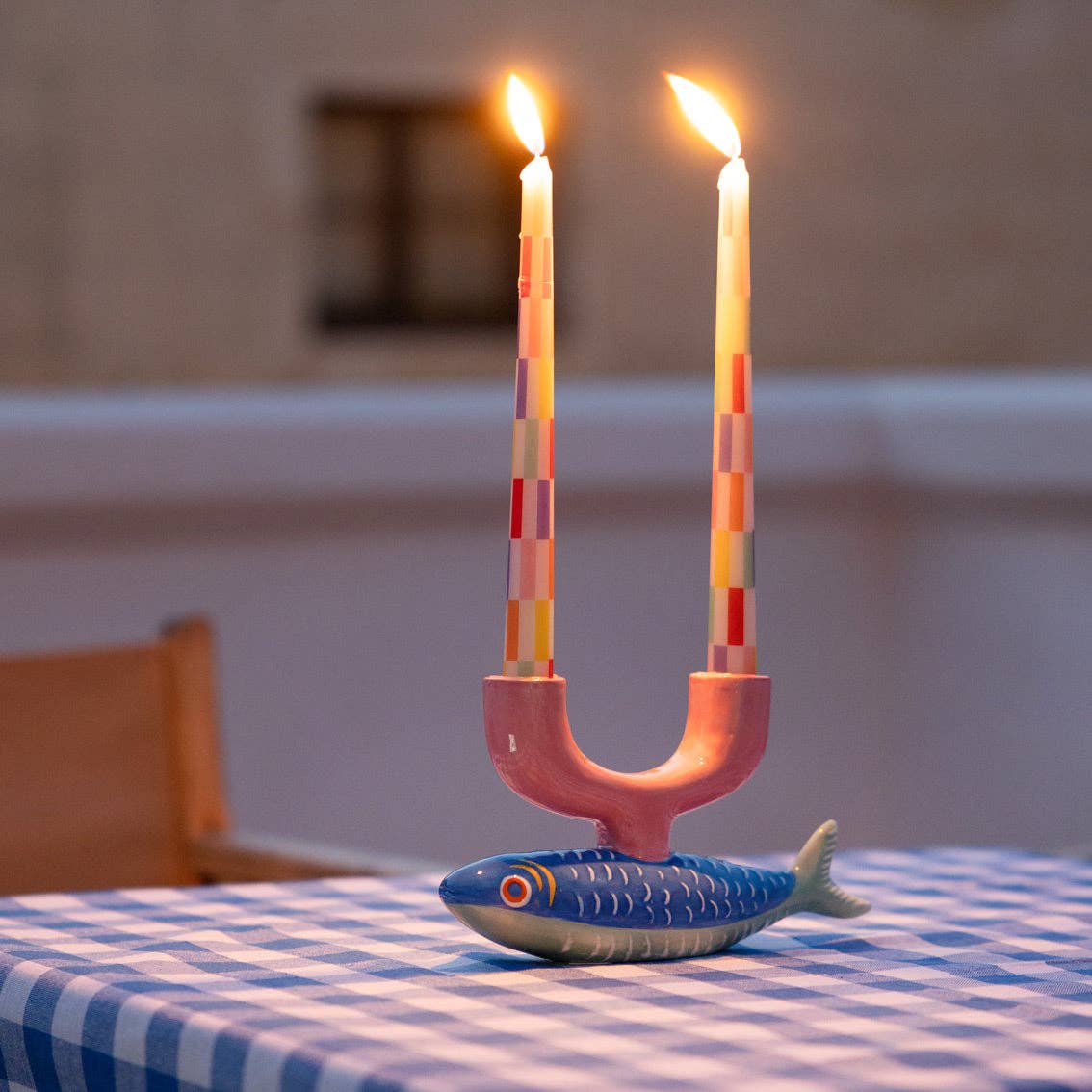 Candle holder with two lit candles on a checkered tablecloth