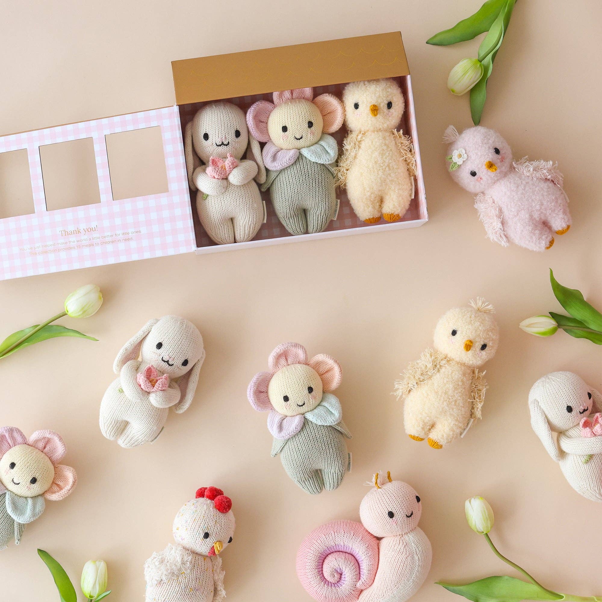 Collection of small plush toys on a beige surface with tulips