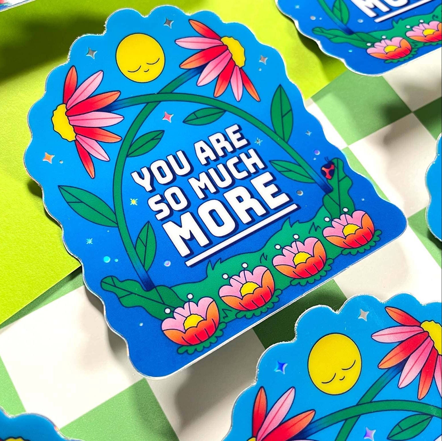 Colorful card with floral design and text 'YOU ARE SO MUCH MORE' on a green and white checkered background.