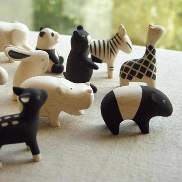 Collection of black and white animal figurines on a light surface with a blurred natural background