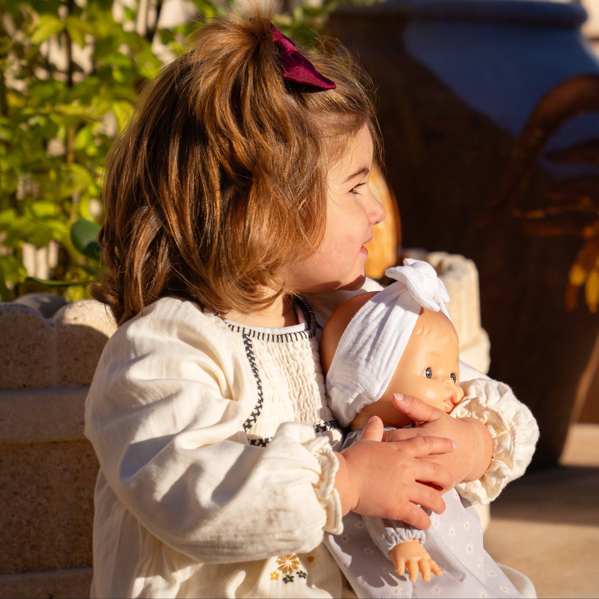 Child holding a doll with a horse in the background