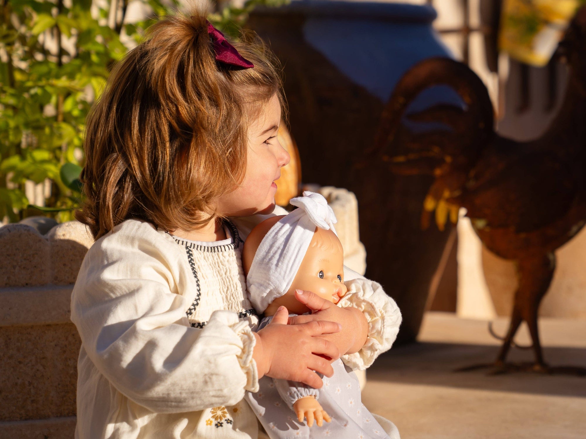 Child holding a doll with a horse in the background