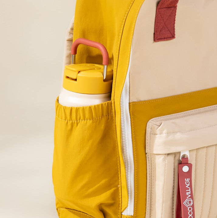 Yellow backpack with a water bottle in a pocket on a beige background
