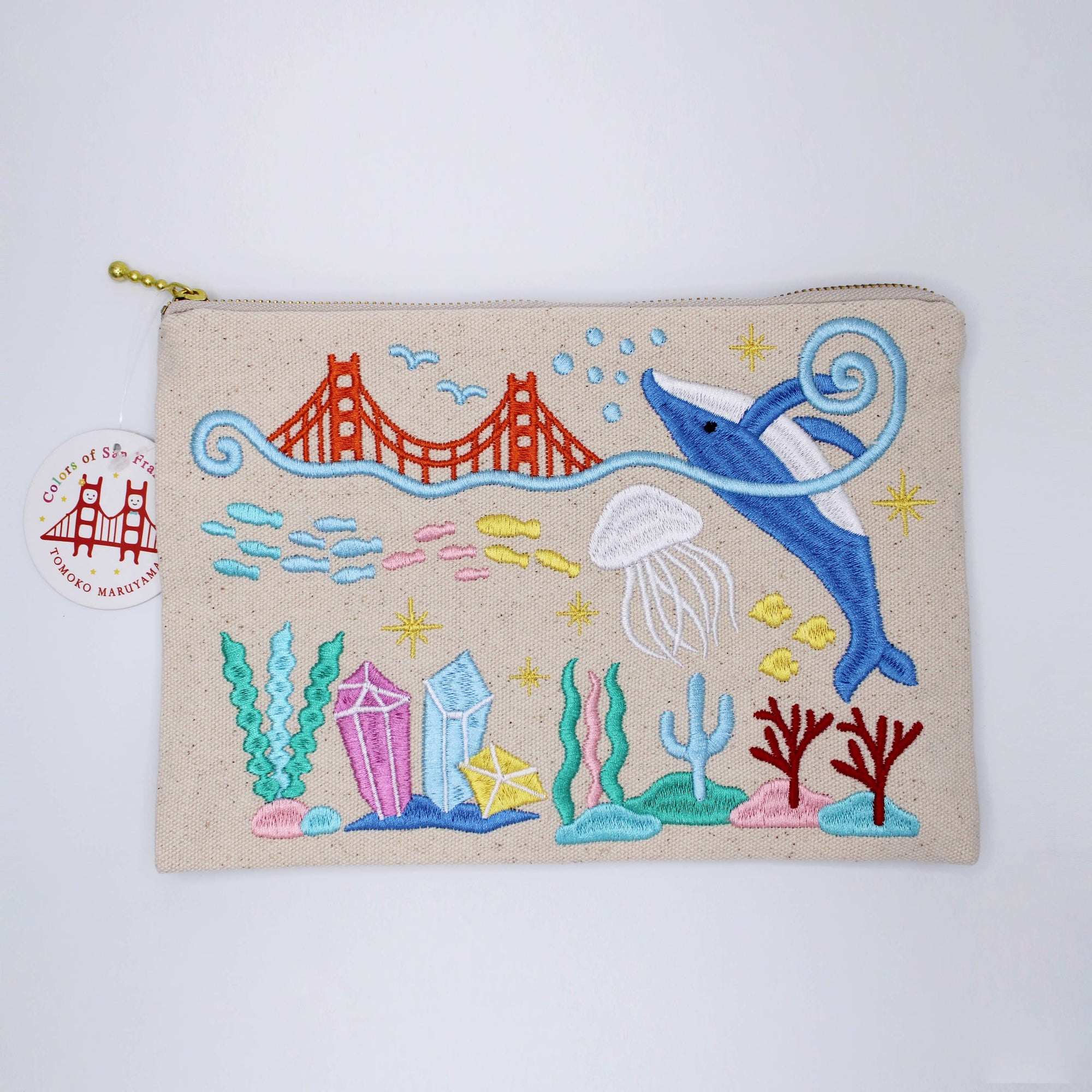 Embroidered pouch with a dolphin, jellyfish, and Golden Gate Bridge design on a beige background.