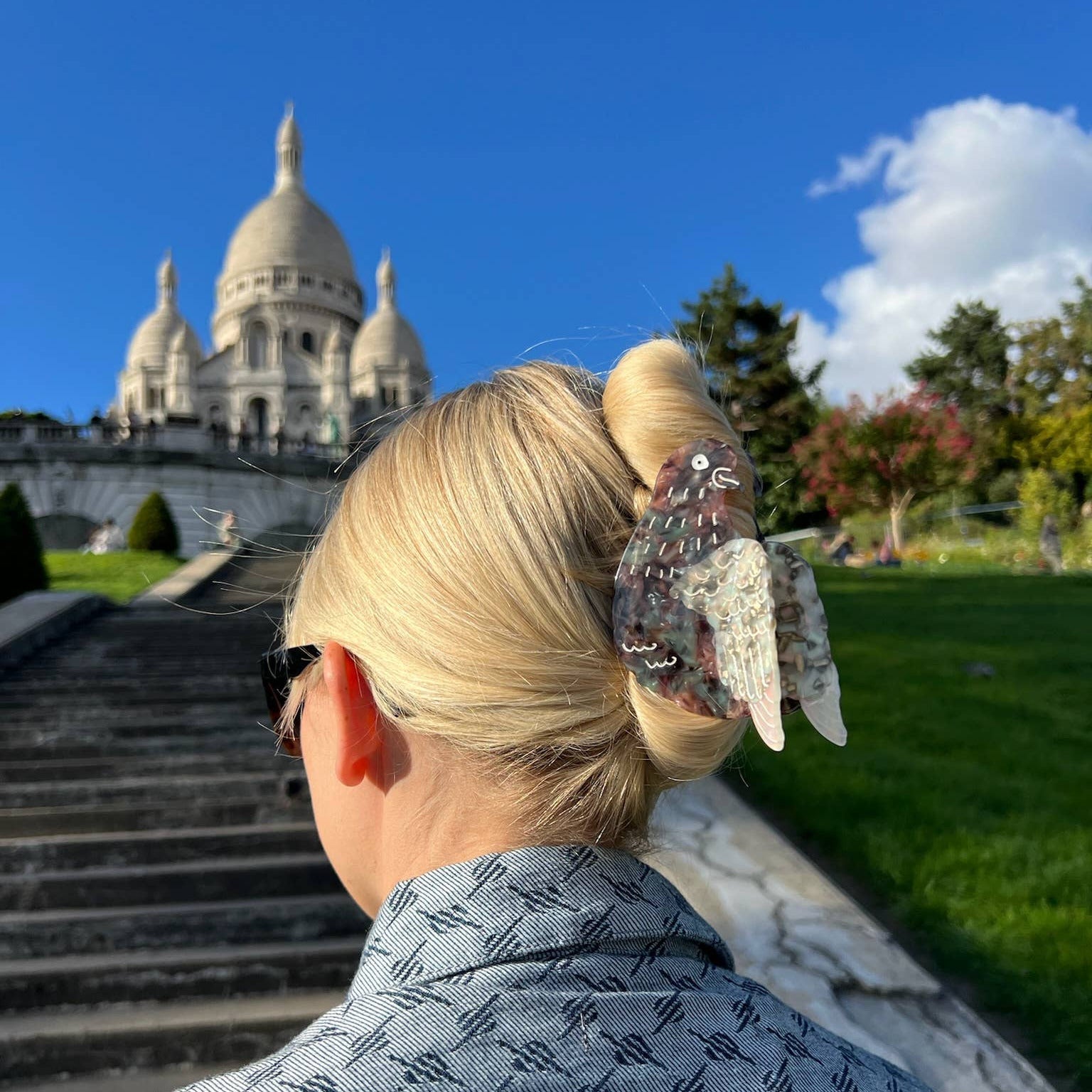 Person with a decorative hair clip standing in front of the Sacré-Cœur Basilica in Montmartre, Paris.
