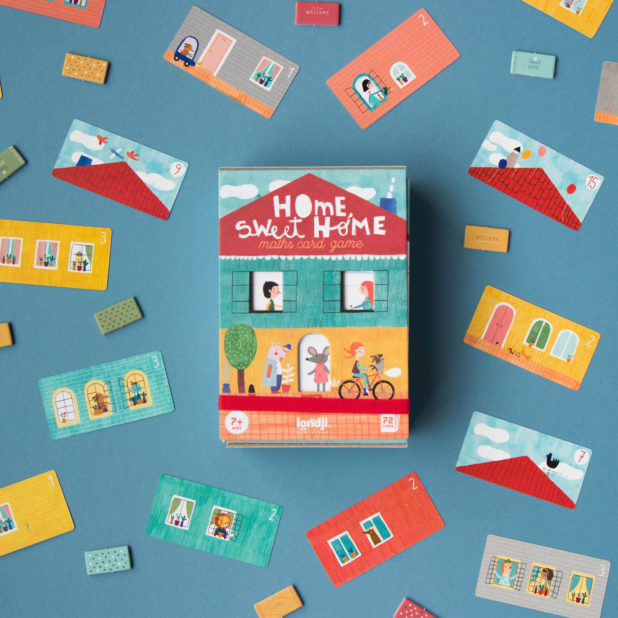 Board game box titled 'Home Sweet Home' surrounded by colorful miniature houses on a blue background