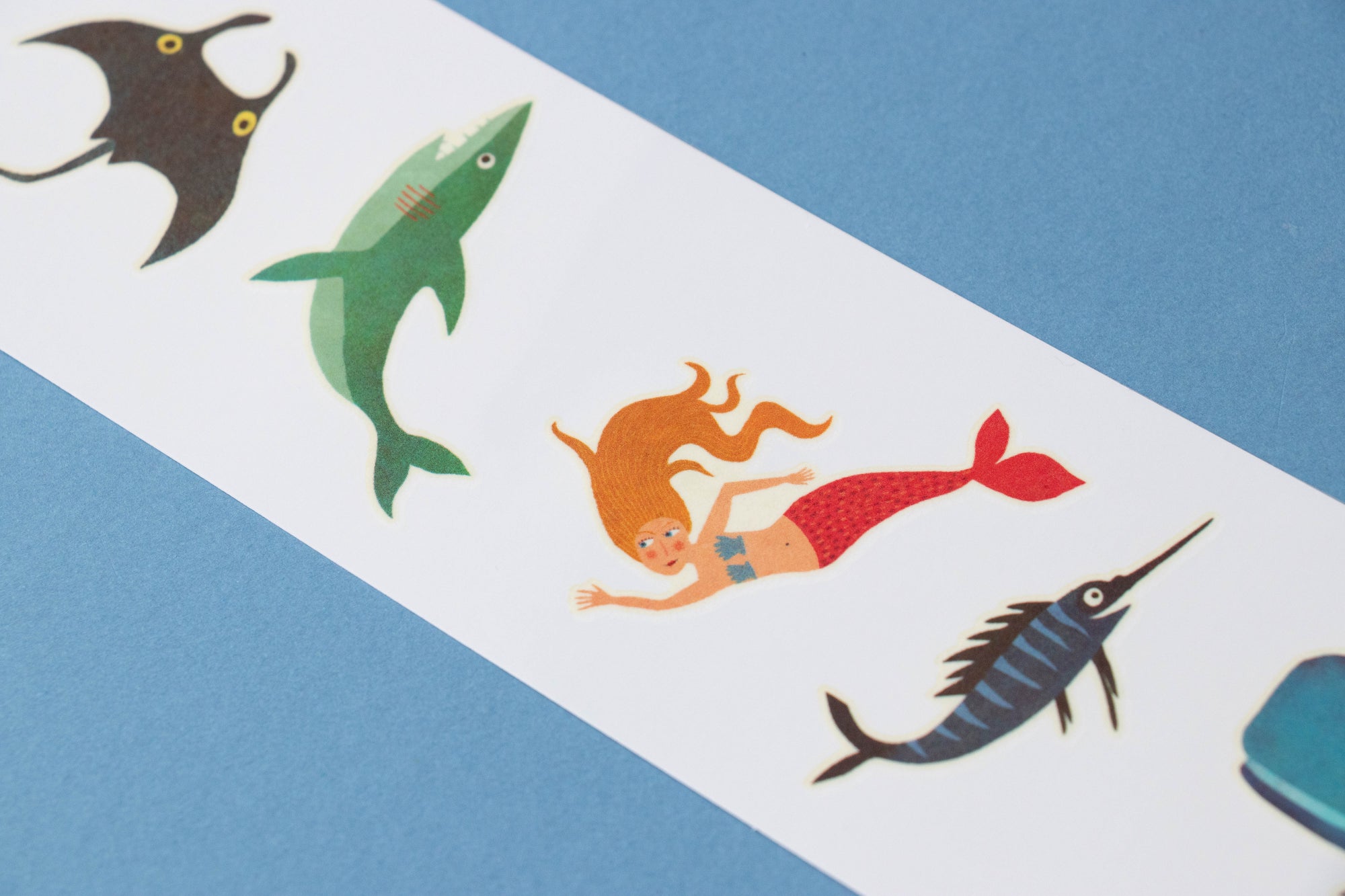 Colorful illustrations of a mermaid and sea creatures on a blue and white striped background.