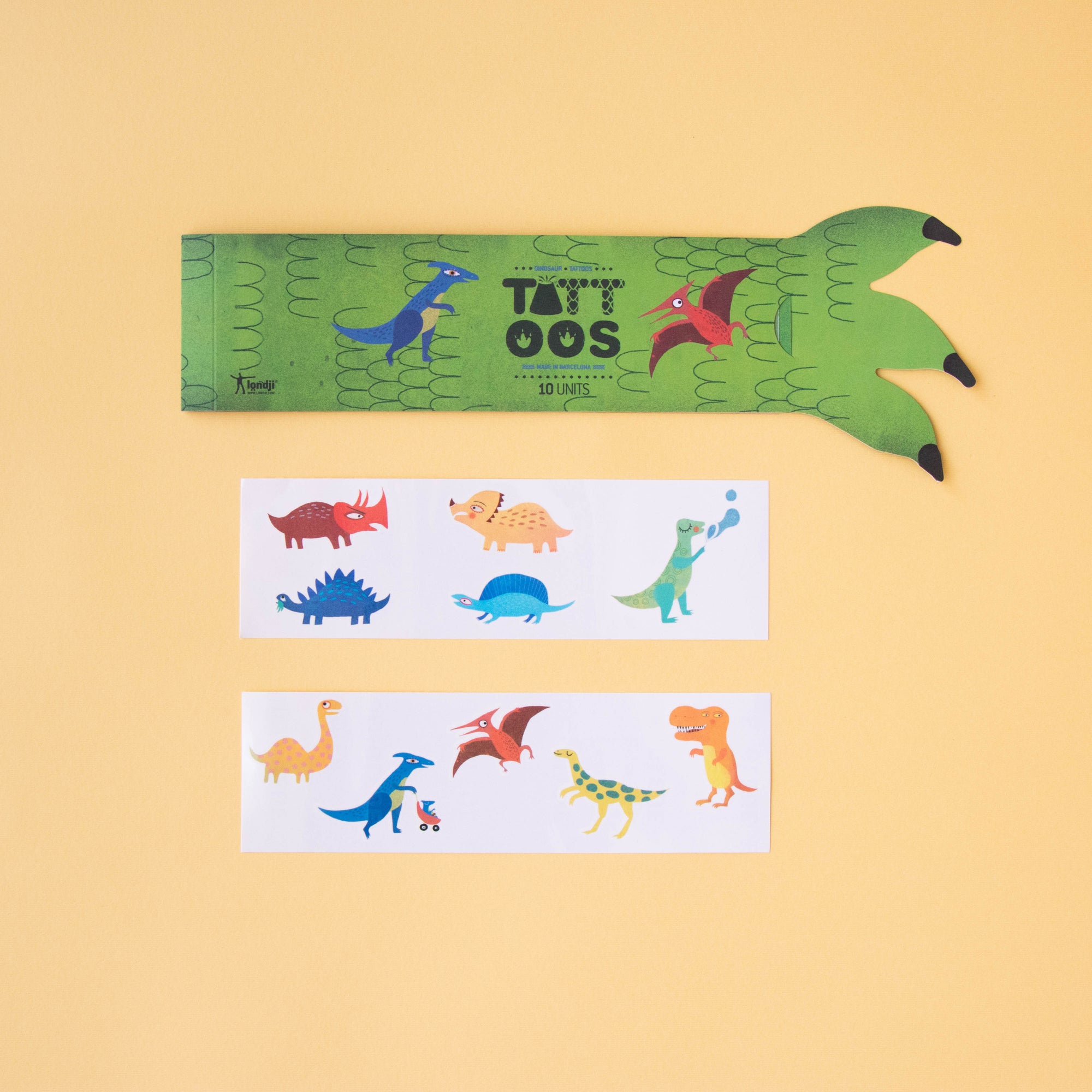 Dinosaur-themed tattoo set with a green case on a beige background