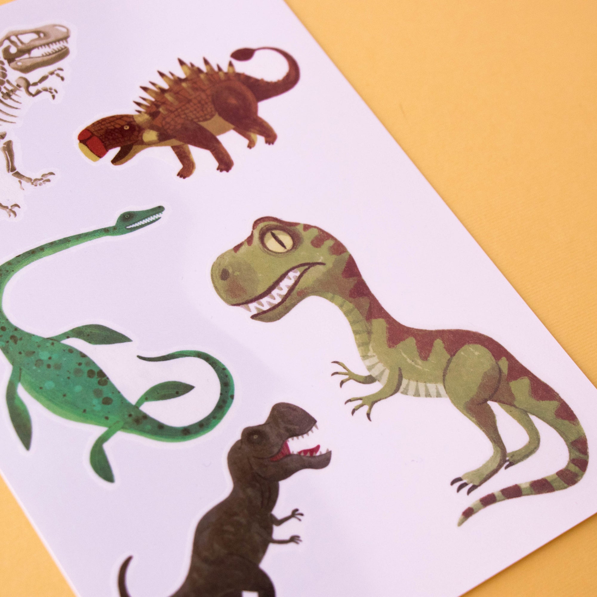 Sheet of dinosaur stickers on a white background with a yellow border