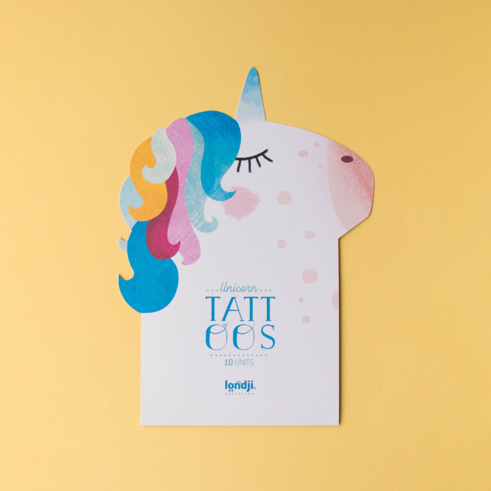 Unicorn-shaped product with 'Tattoos' branding on a yellow background
