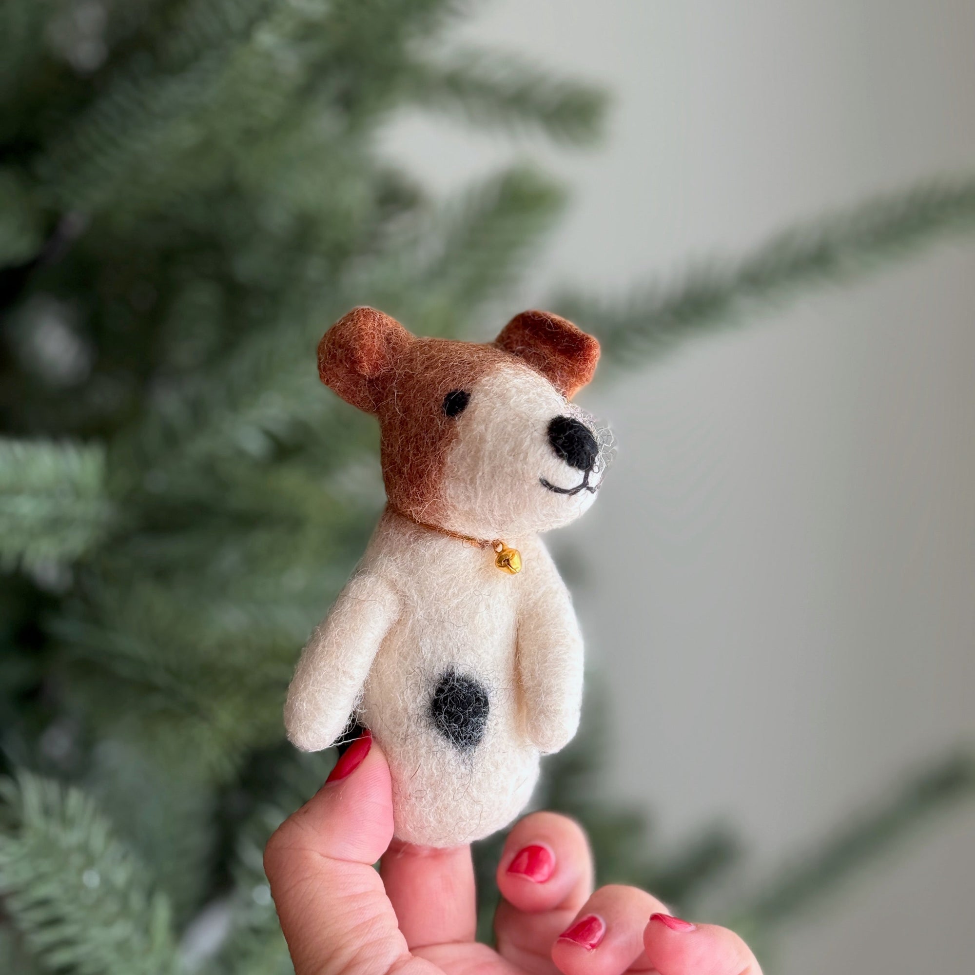 Small felt dog toy held in a hand with a blurred green background