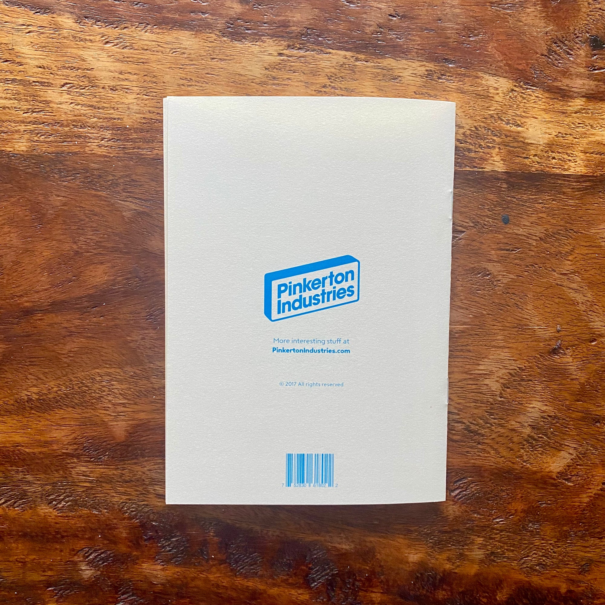 White book or notebook with a blue logo and text on a wooden surface