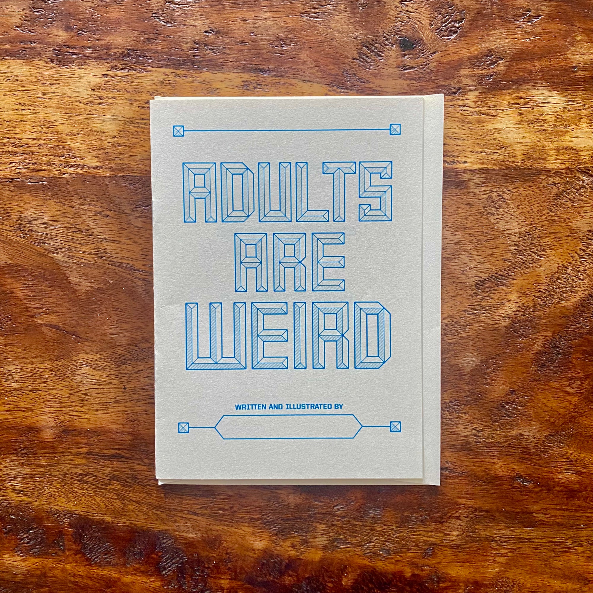 Book titled 'Adults Are Weird' on a wooden surface