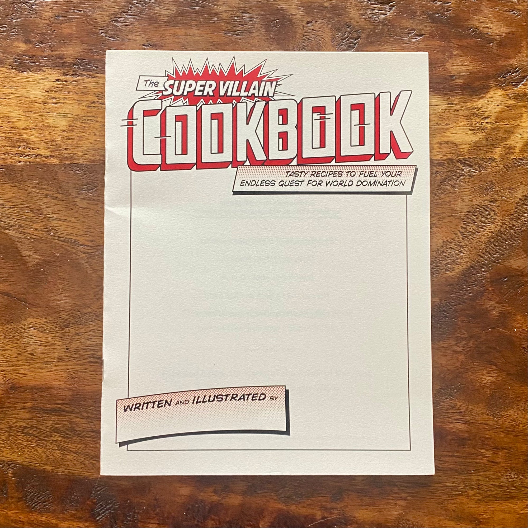 Cookbook titled 'The Super Villain Cookbook' on a wooden surface