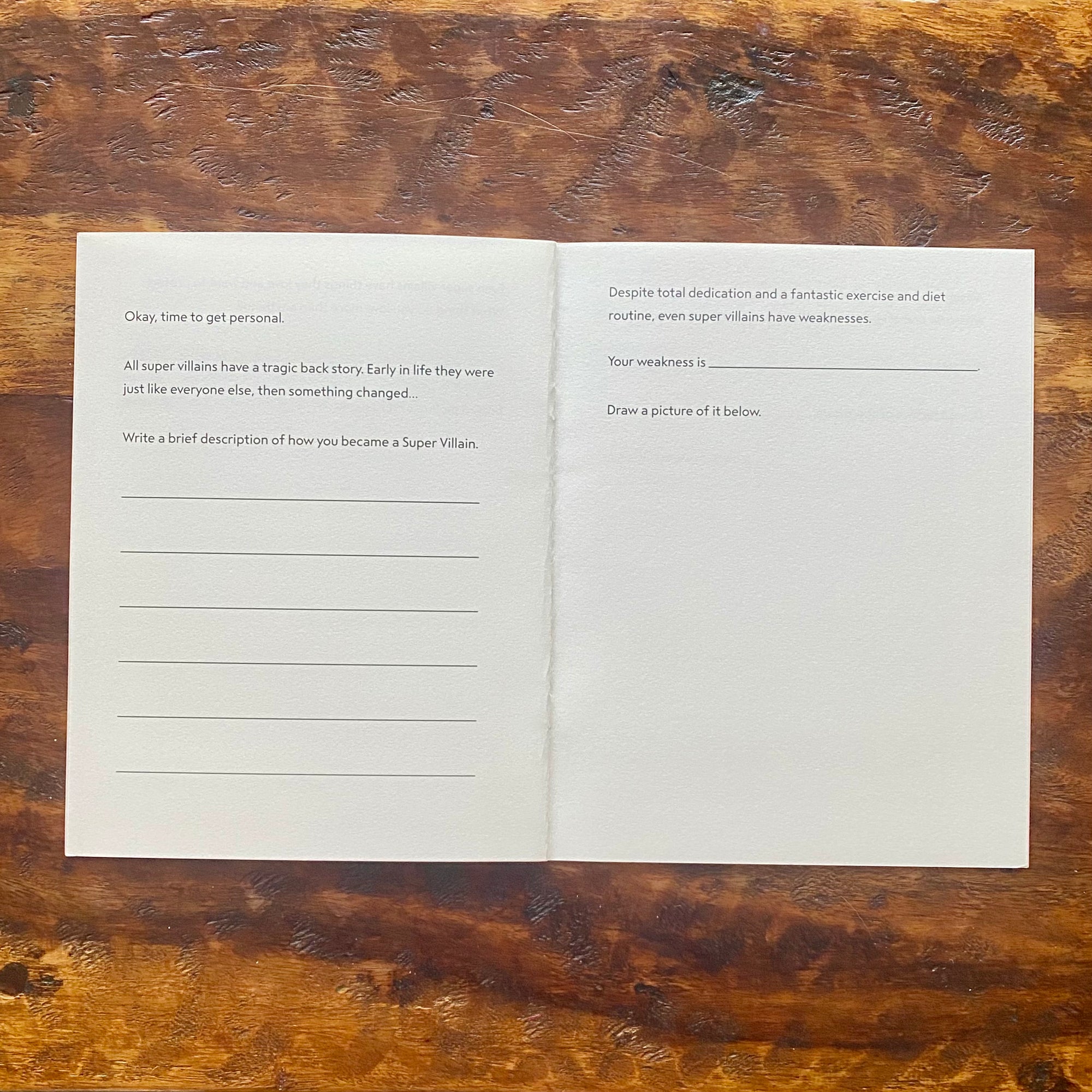 Open book with writing prompts on a wooden surface