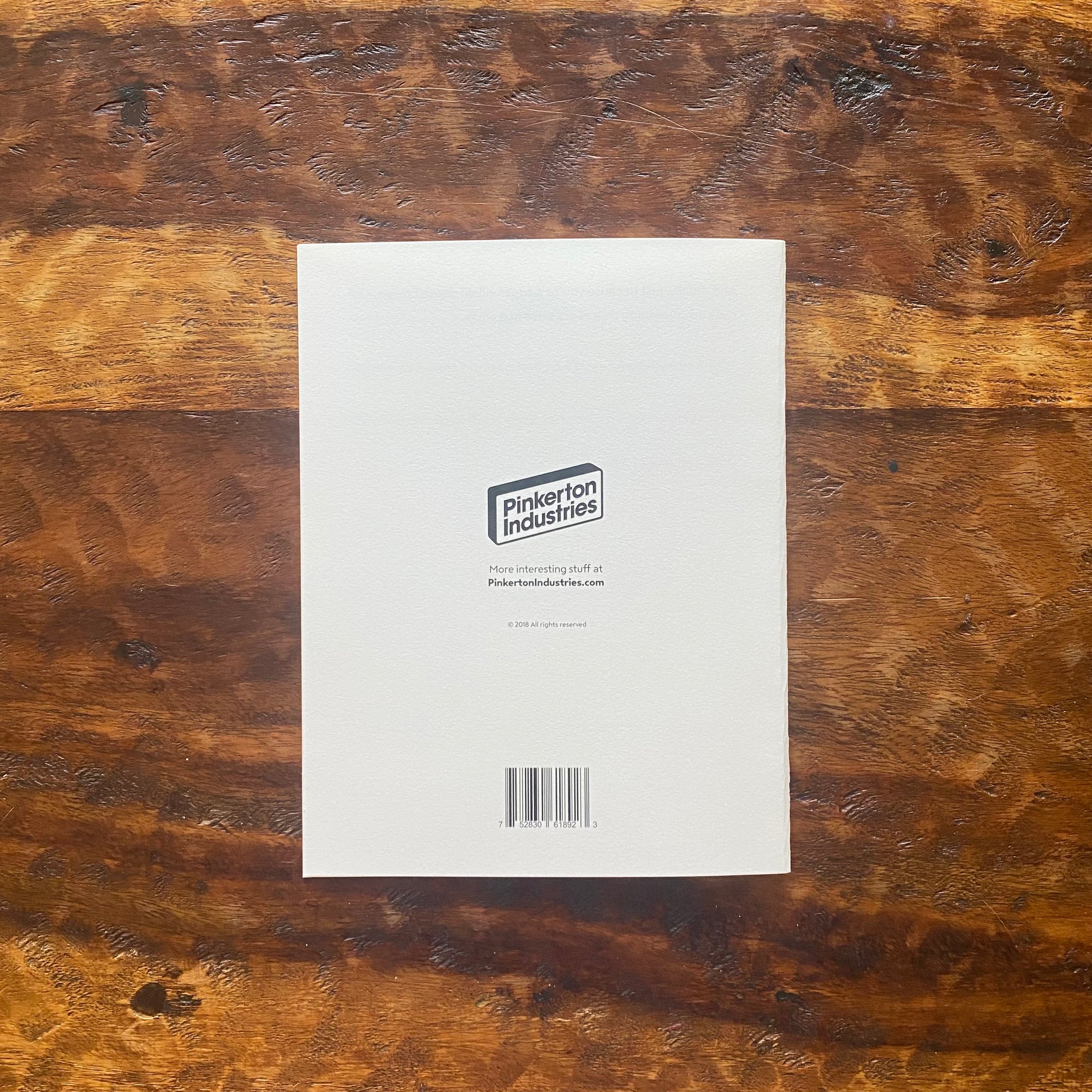 White product packaging with a Pinkerton Industries logo on a wooden surface
