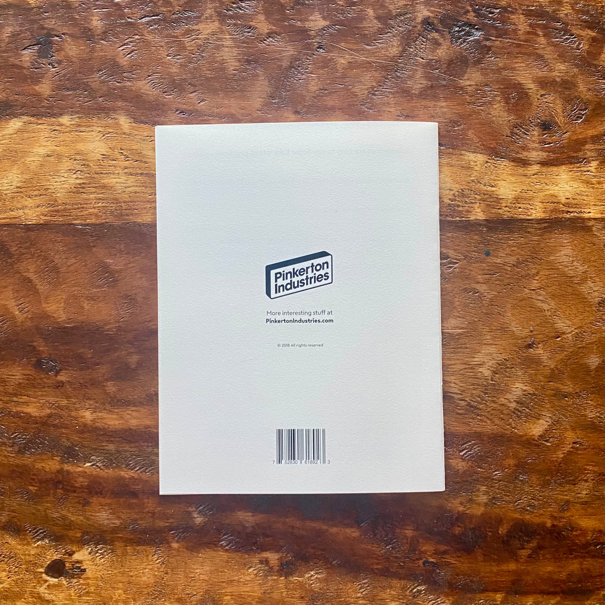 White paper with a Pinkerton Industries logo on a wooden surface