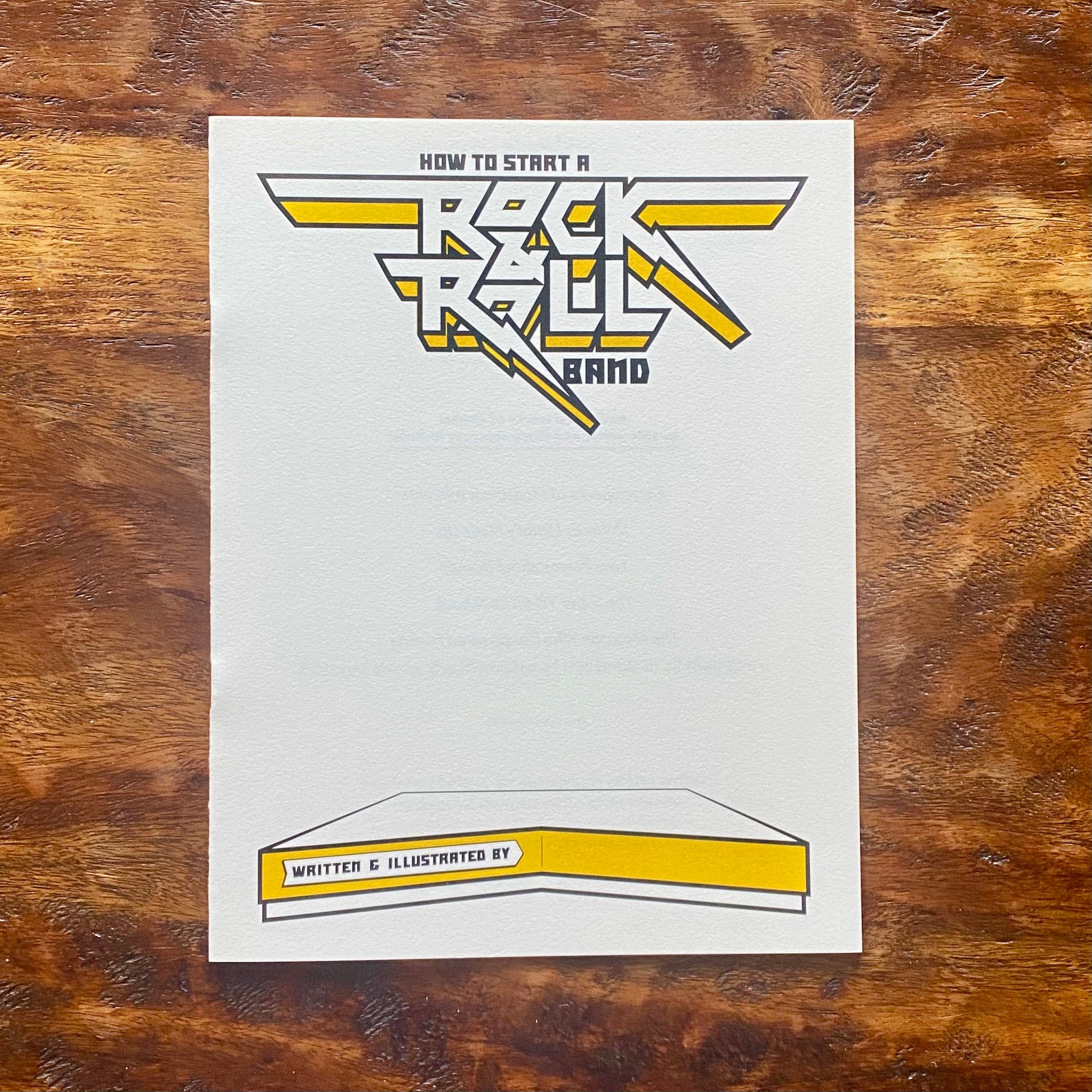 Booklet titled 'How to Start a Rock & Roll Band' on a wooden surface