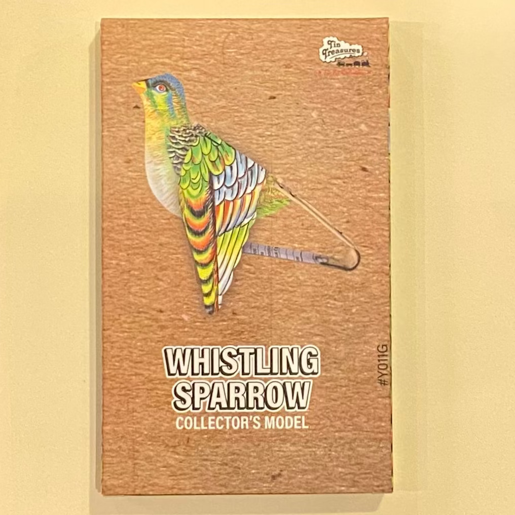 box with a colorful parrot illustration and text on a wooden surface