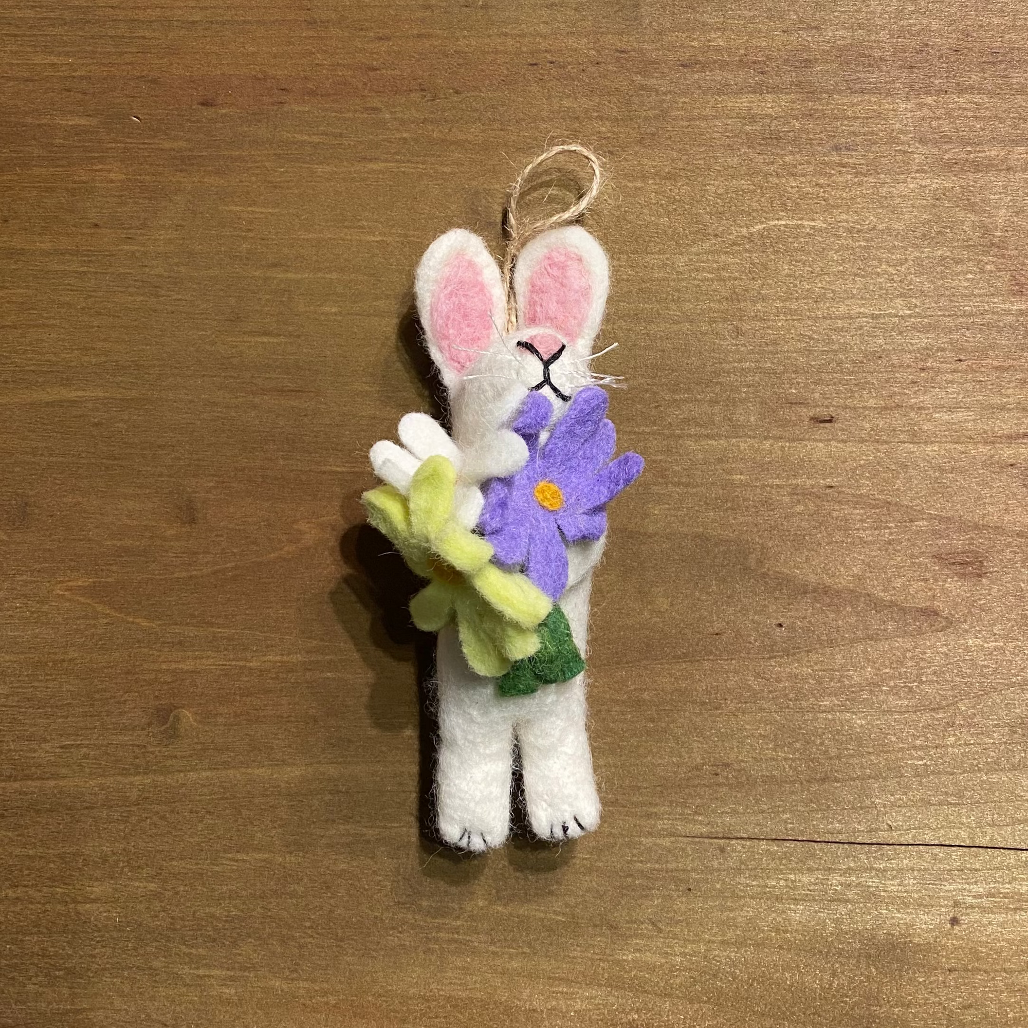 White bunny ornament with a purple flower on a wooden surface