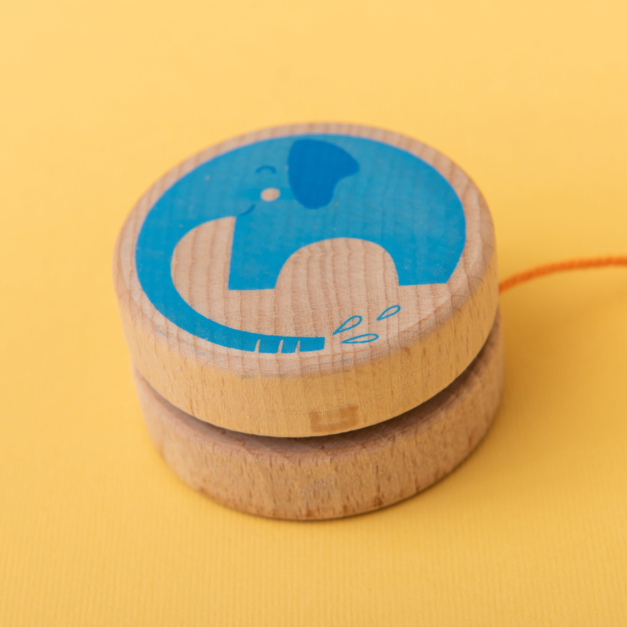 Wooden yoyo with blue elephant design on a yellow background