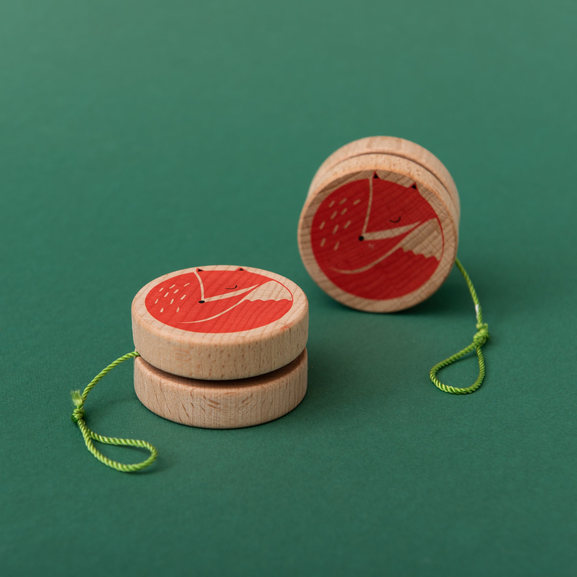 Wooden yoyos with red fox designs on a green background