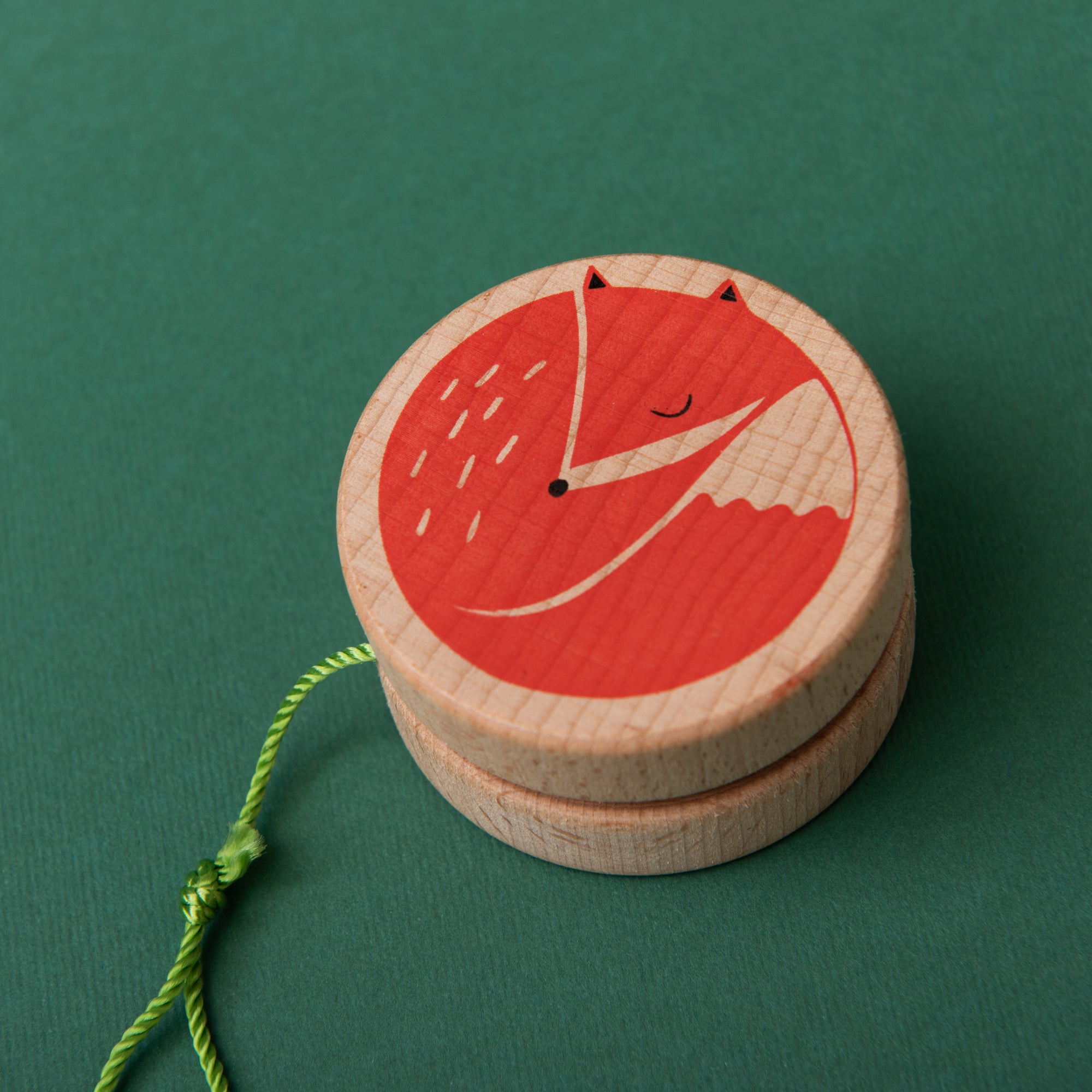 Wooden yo-yo with a red fox design on a green background