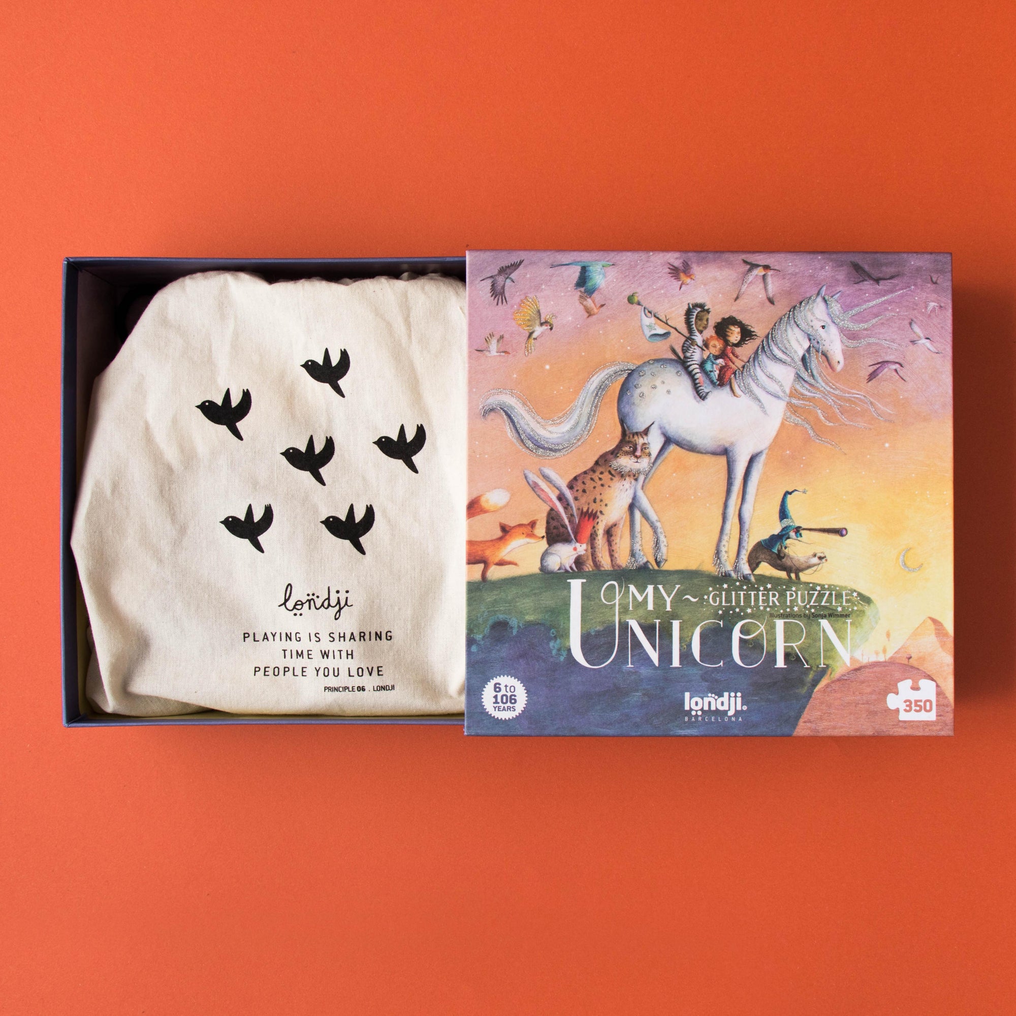 Product packaging with a white garment and colorful unicorn illustration on an orange background