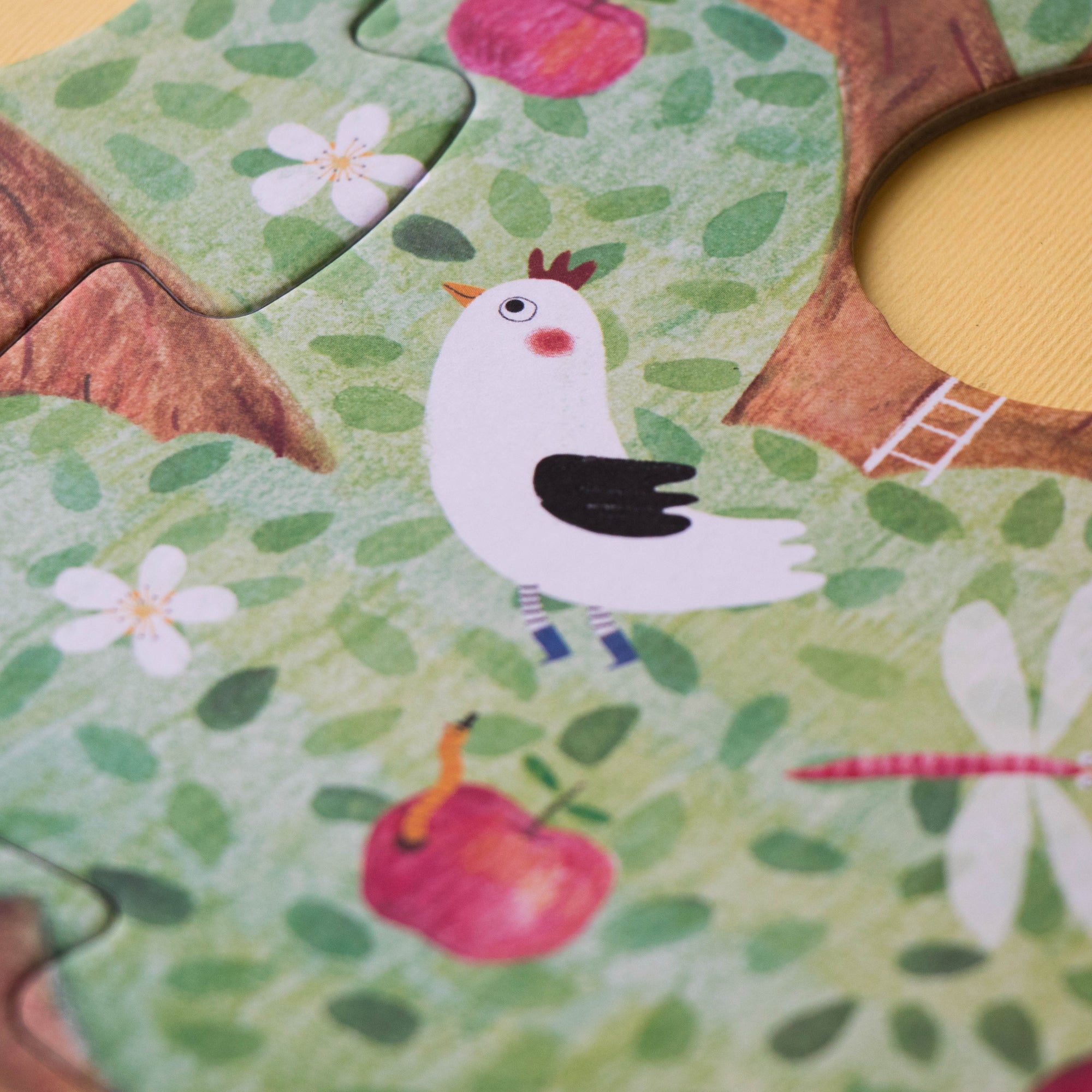 Children's puzzle with a bird, tree, and flowers on a green background