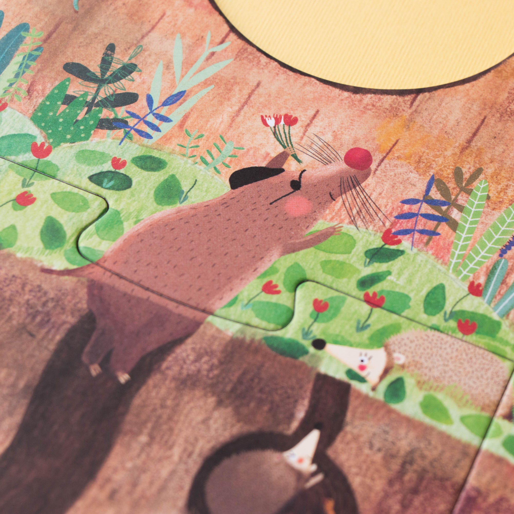 Illustration of a garden scene with plants and animals on a wooden surface.