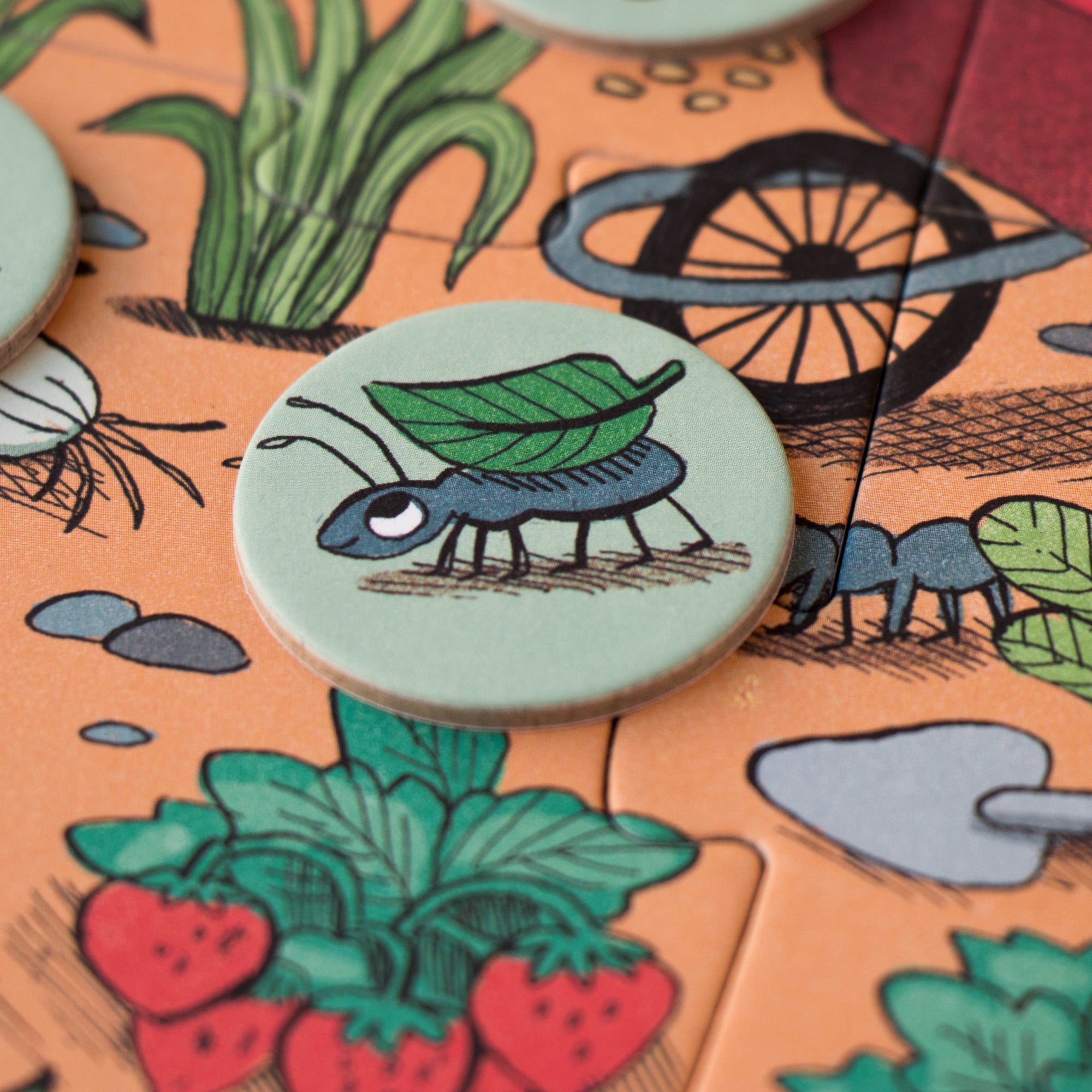 Close-up of a board game piece with a caterpillar design on a garden-themed board.
