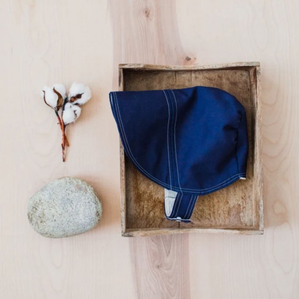 blue sun hat in wooden box witha cotton twig and rock
